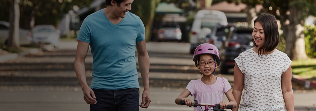 Madre y padre enseñando a su hija a montar en bicicleta. Empresario Amway: tu propio negocio a tu ritmo.