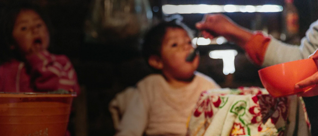 Foto de una mujer alimentando con una cuchara a un niño. Amway generando impacto en la comunidad. Responsabilidad Social.